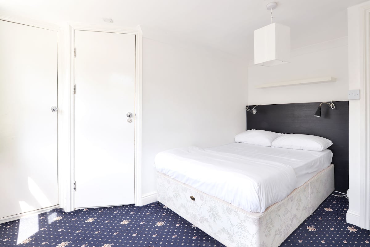 A bedroom with a bed, a wardrobe, and a nightstand.