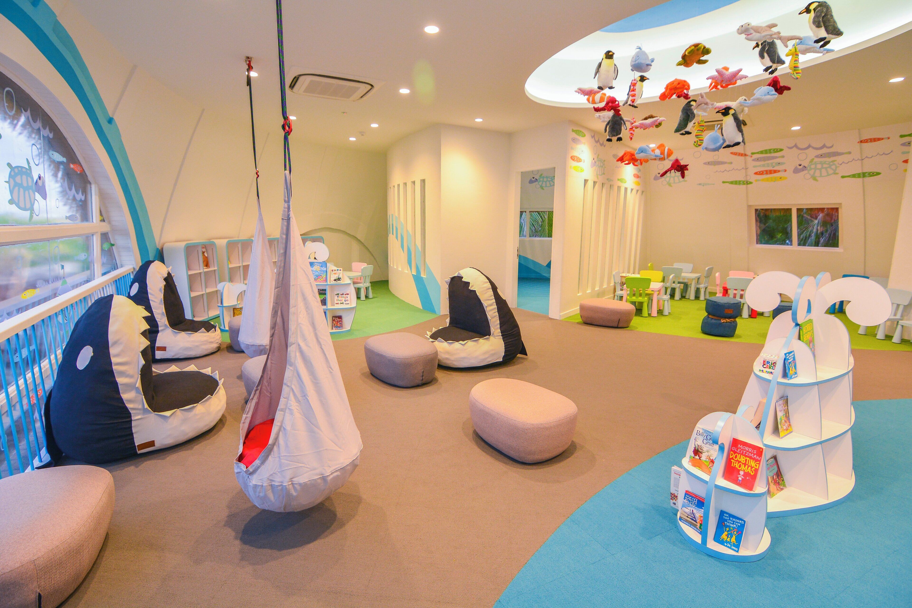 A children's playroom with bean bags, a reading area, and a wall decorated with animal figures.