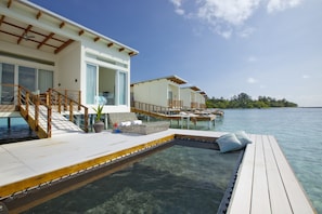 A resort with overwater bungalows connected by a wooden deck, clear blue water, and a tropical landscape. - Holiday Inn Resort Kandooma Maldives by IHG (Kandooma)
