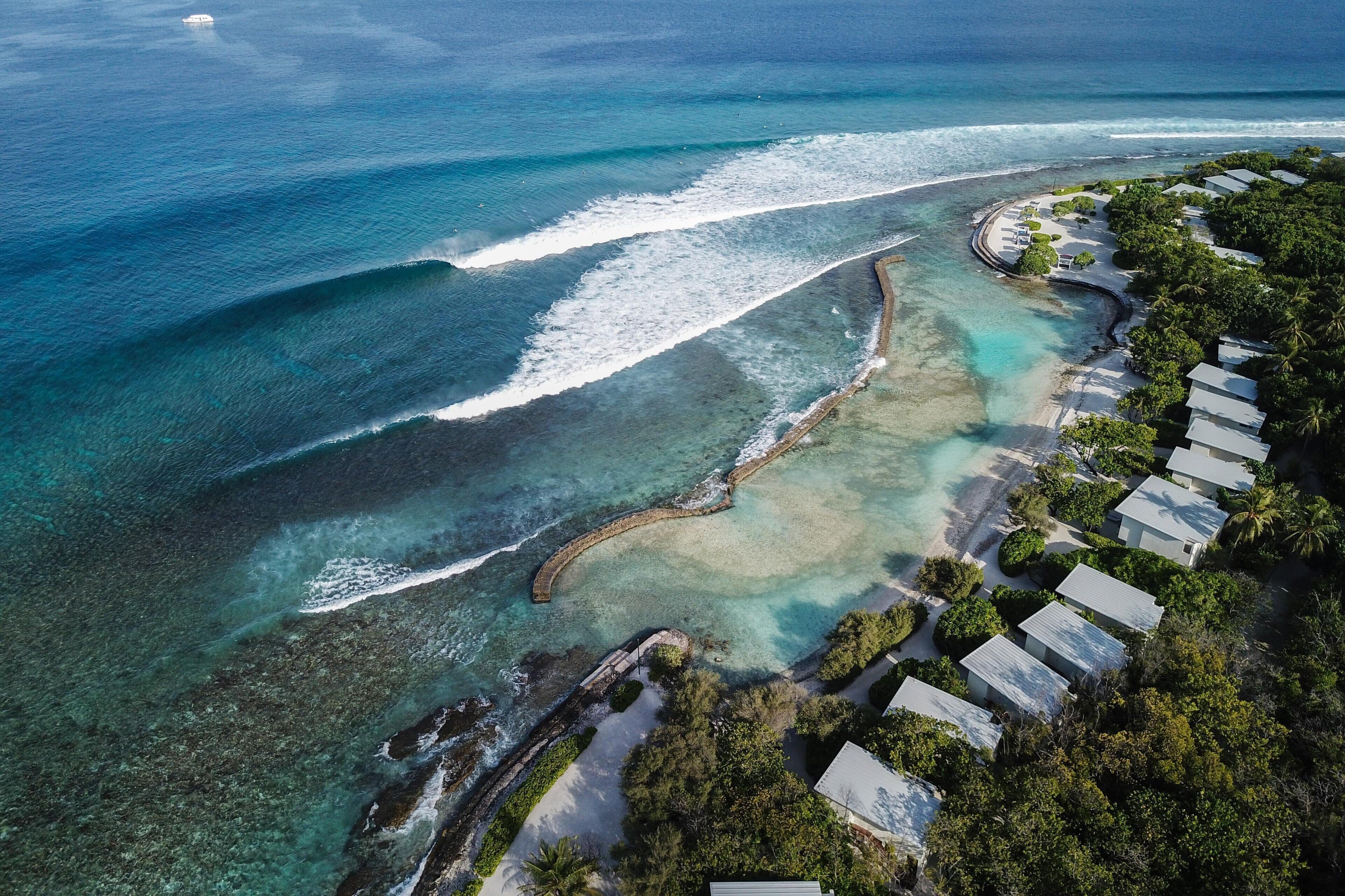 Luftaufnahme eines Küstenresorts mit Strandvillen, klarem, blauem Wasser und einem Sandstrand.