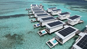 An overwater resort with multiple bungalow-style accommodations, each with a private pool and solar panels. - Holiday Inn Resort Kandooma Maldives by IHG (Kandooma)