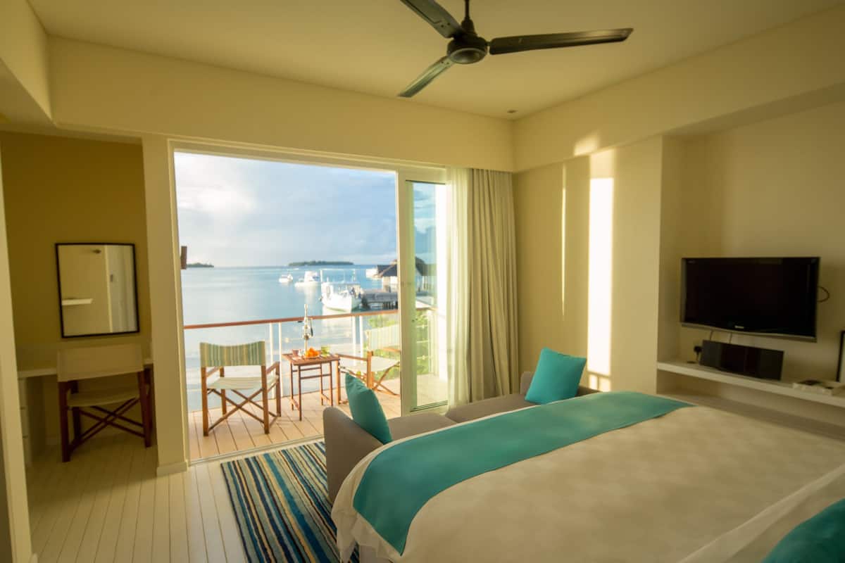 A hotel room with a balcony, a bed, a TV, and a desk.