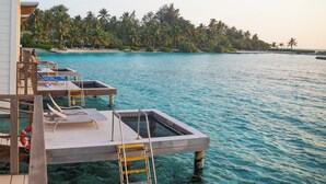 A wooden dock with lounge chairs and a pool, overlooking a turquoise sea and palm trees. - Holiday Inn Resort Kandooma Maldives by IHG (Kandooma)