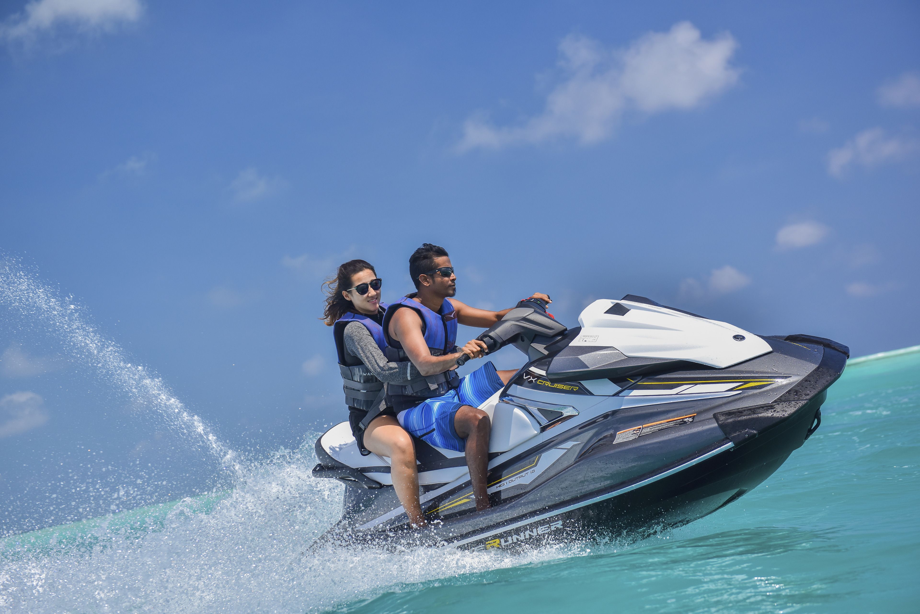 Two people on a jet ski in turquoise water.