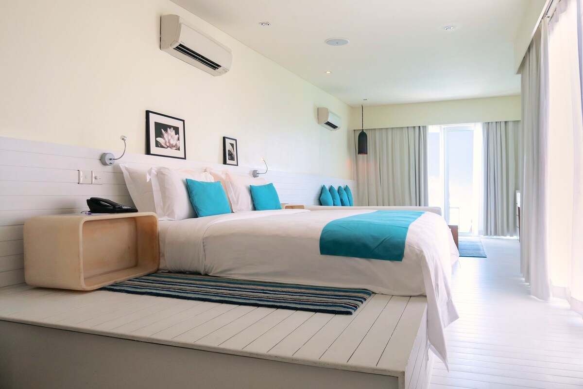 Une chambre d’hôtel moderne avec un grand lit, une table de chevet, un téléphone et un tableau au mur.