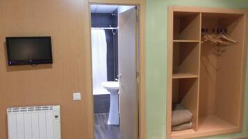 A room with a wooden wardrobe, a radiator, and a television on the wall.