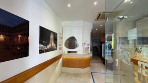 A hotel lobby with a reception desk, framed photographs on the walls, and a glass display case. - Hotel Condedu Badajoz (Badajoz)