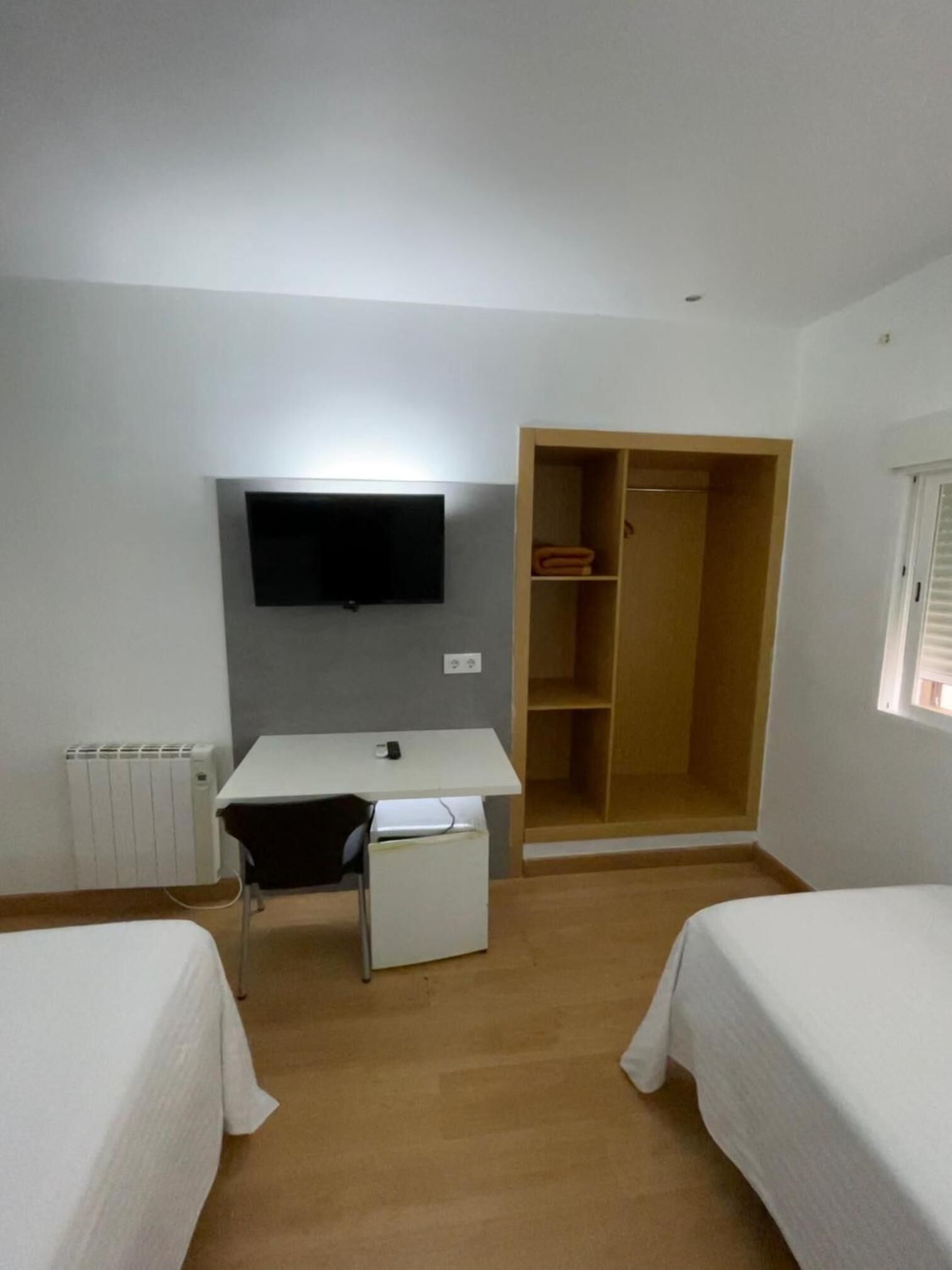 A room with a bed, a desk, a chair, a wardrobe, and a television.