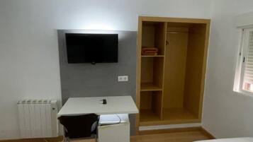 A room with a bed, a desk, a chair, a wardrobe, and a television.