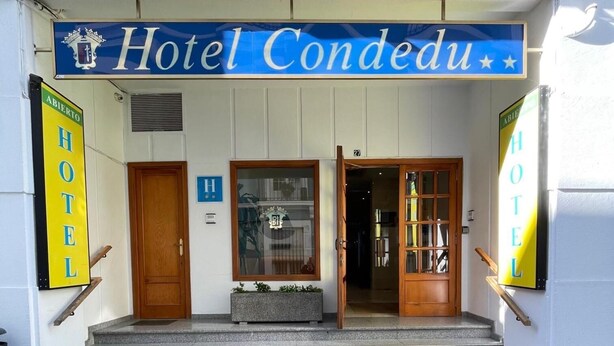 The entrance to Hotel Condedu with a sign above the doors, a staircase leading up, and a small planter on the steps. - Hotel Condedu Badajoz (Badajoz)