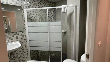 Un baño con cabina de ducha, inodoro y lavamanos.