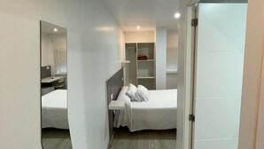 A modern hotel room with a bed, a desk, a wardrobe, and a mirror. - Hotel Condedu Badajoz (Badajoz)