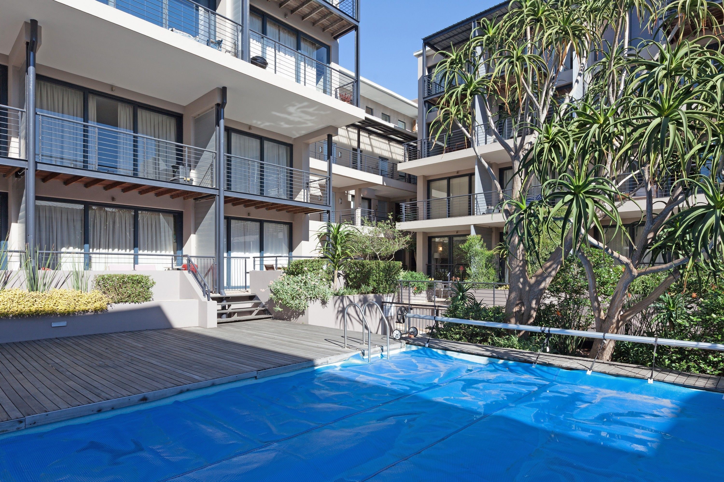 Una piscina al aire libre, sombrillas, sillones reclinables de piscina