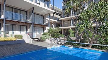 Una piscina al aire libre, sombrillas, sillones reclinables de piscina
