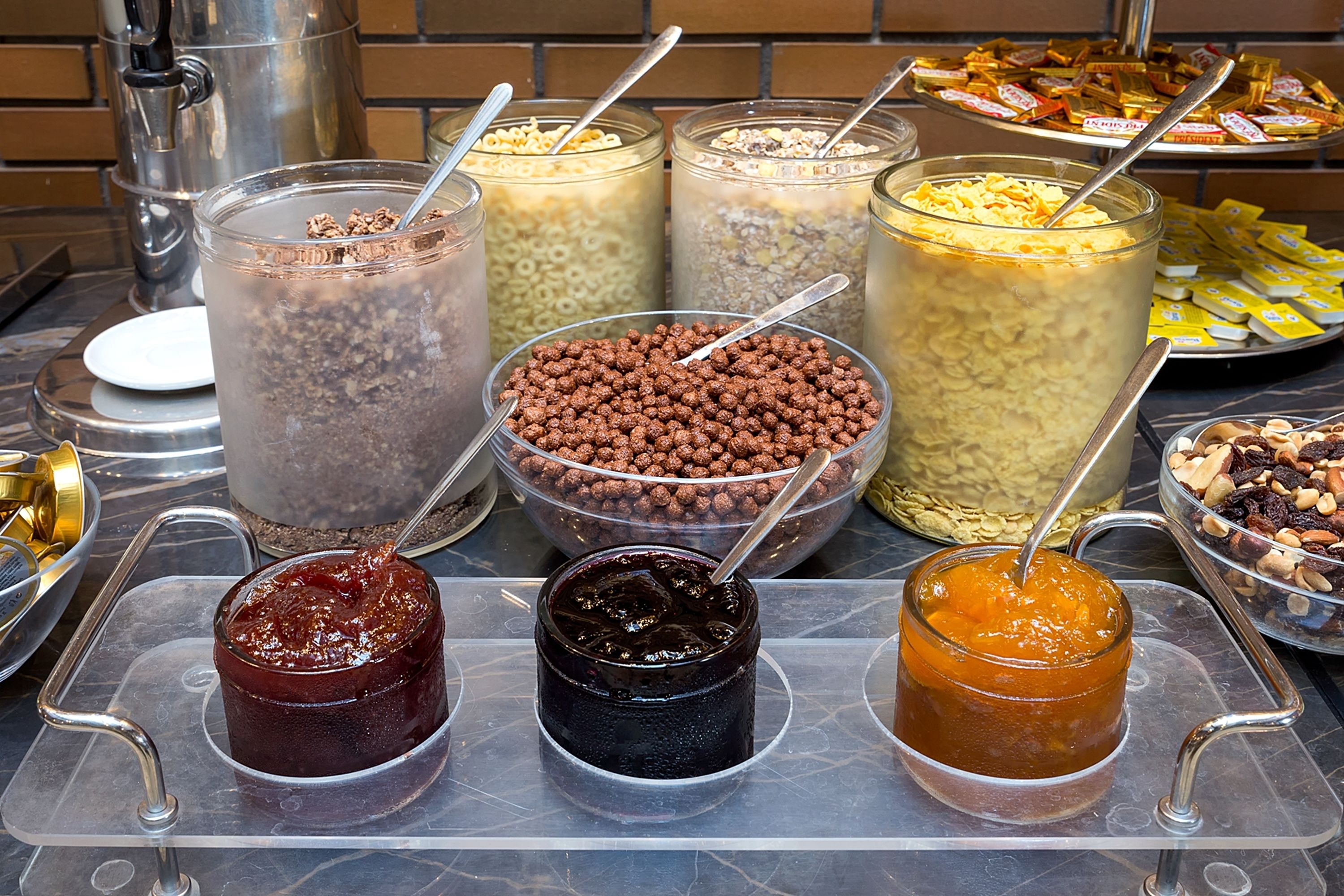 A buffet with various food items including cereals, nuts, and spreads.