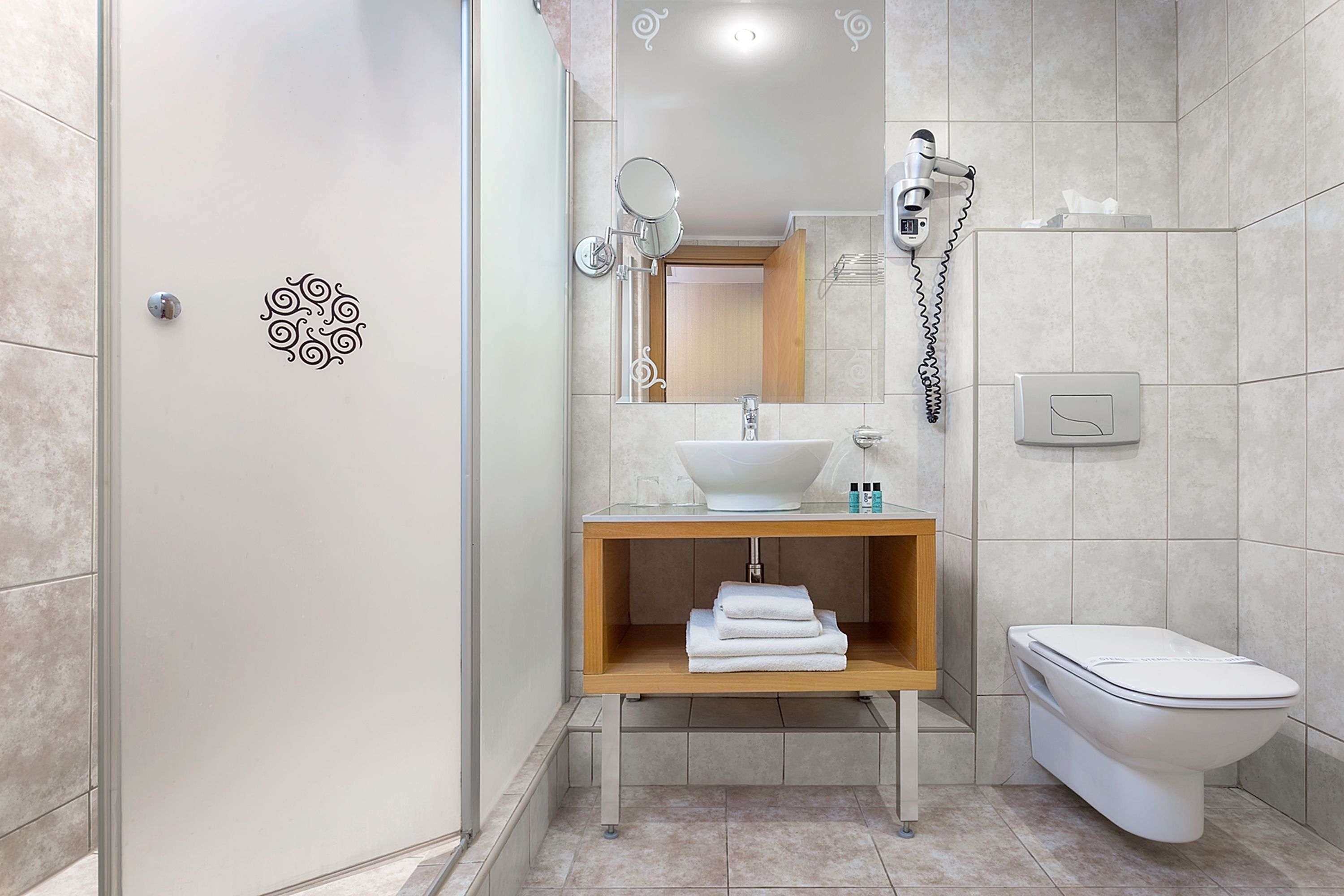 A modern bathroom with a white sink, wooden vanity, and a toilet.