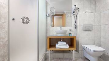 A modern bathroom with a white sink, wooden vanity, and a toilet.