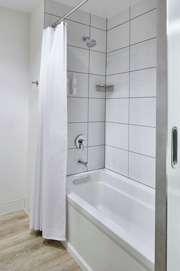 A modern bathroom with a white bathtub, a shower with a rain showerhead, and a white shower curtain.
