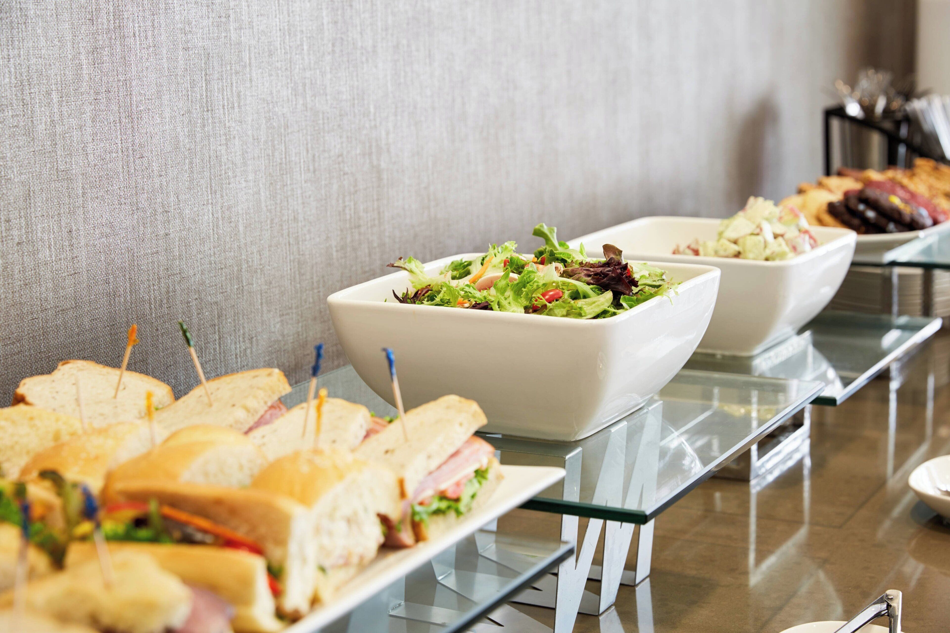 A buffet table with sandwiches and salads.
