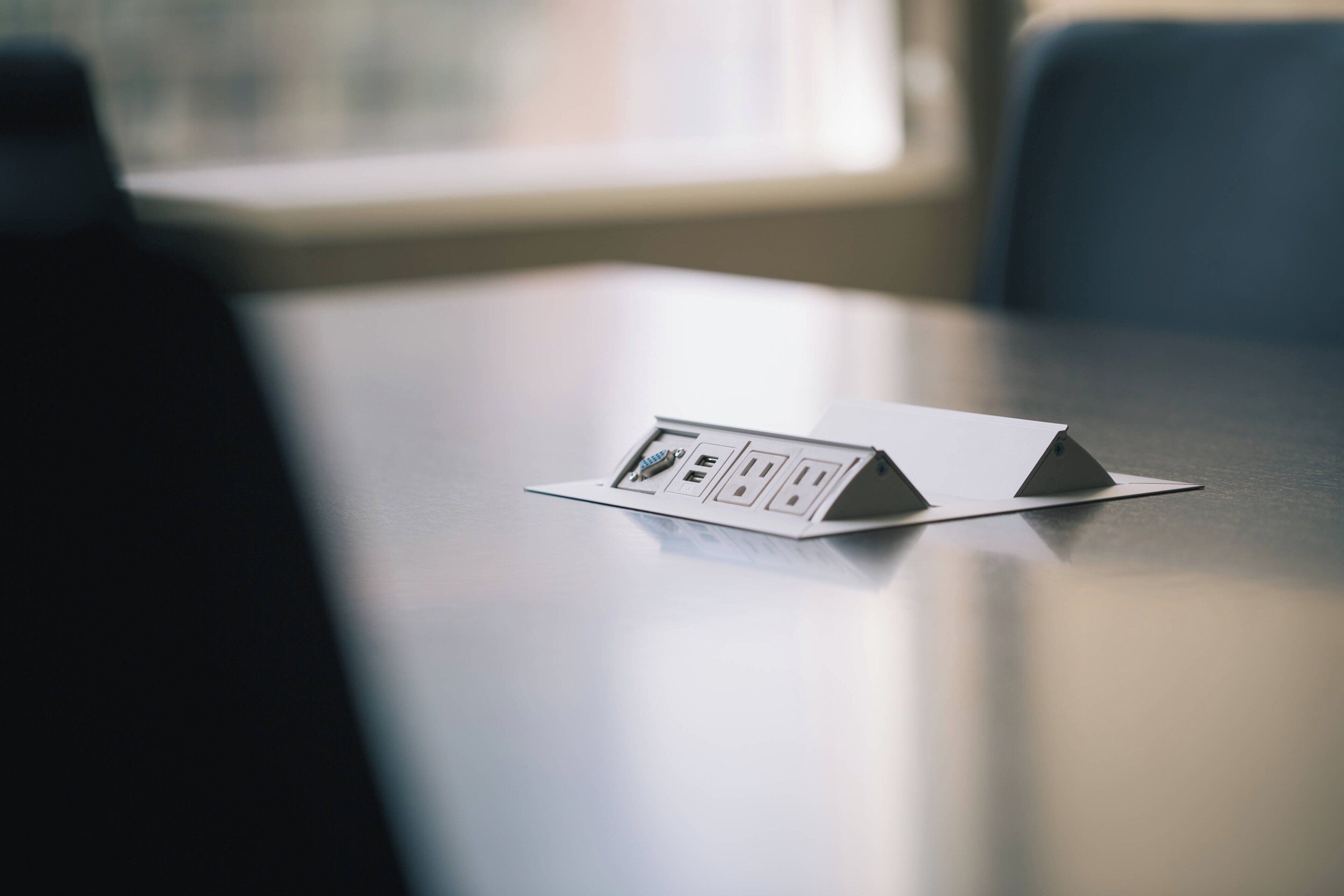 A modern table with a power strip and a small device, likely a charging station, on it.
