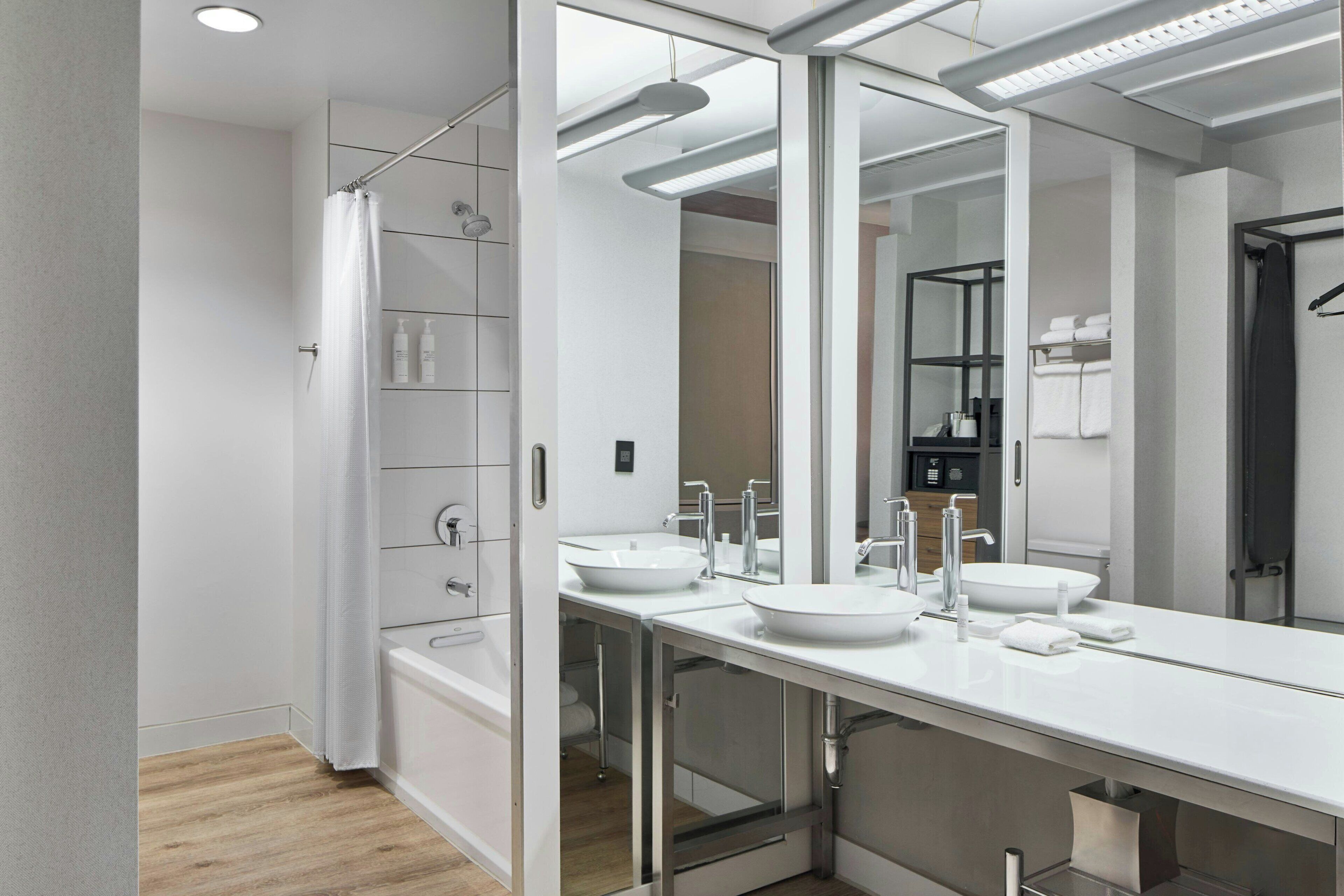 A modern bathroom with a walk-in shower, two sinks, and a large mirror.