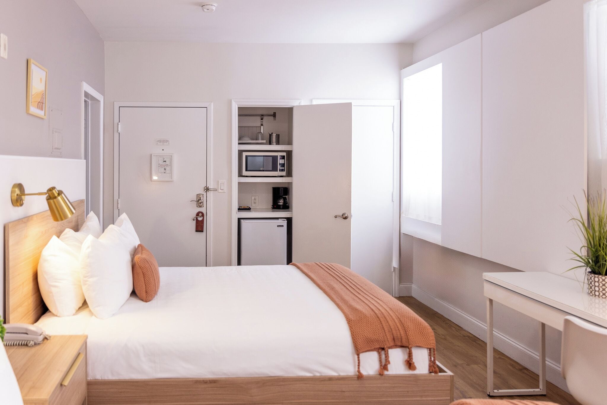 Une chambre moderne avec un lit, une table de chevet et une petite kitchenette.