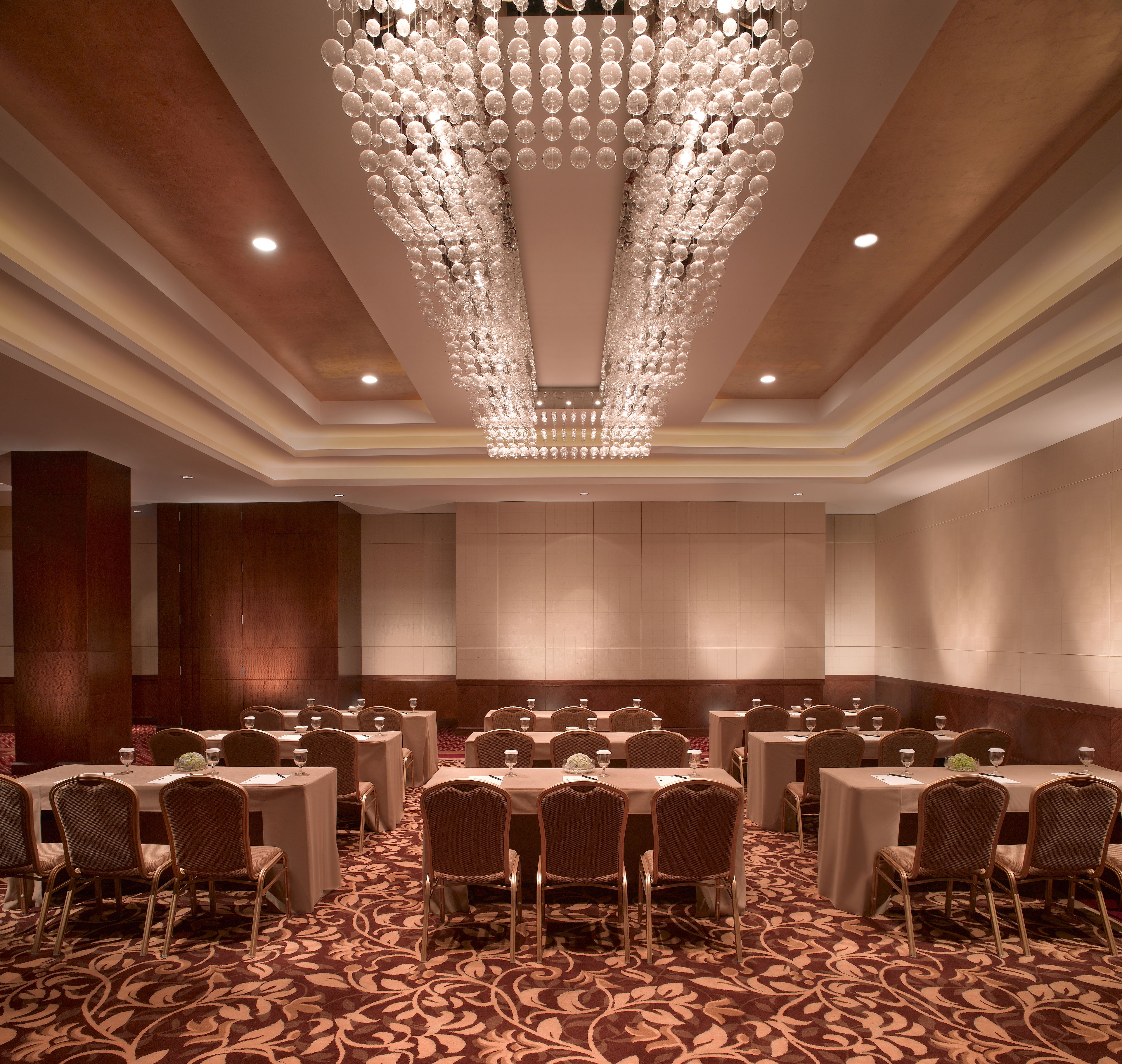 A conference room with round tables, chairs, and a large chandelier.