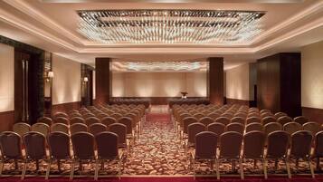 A conference room with rows of chairs, a patterned carpet, and a chandelier.