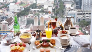 A breakfast table with various dishes, a coffee pot, and a view of a cityscape. - JW Marriott Hotel Medan (Medan)