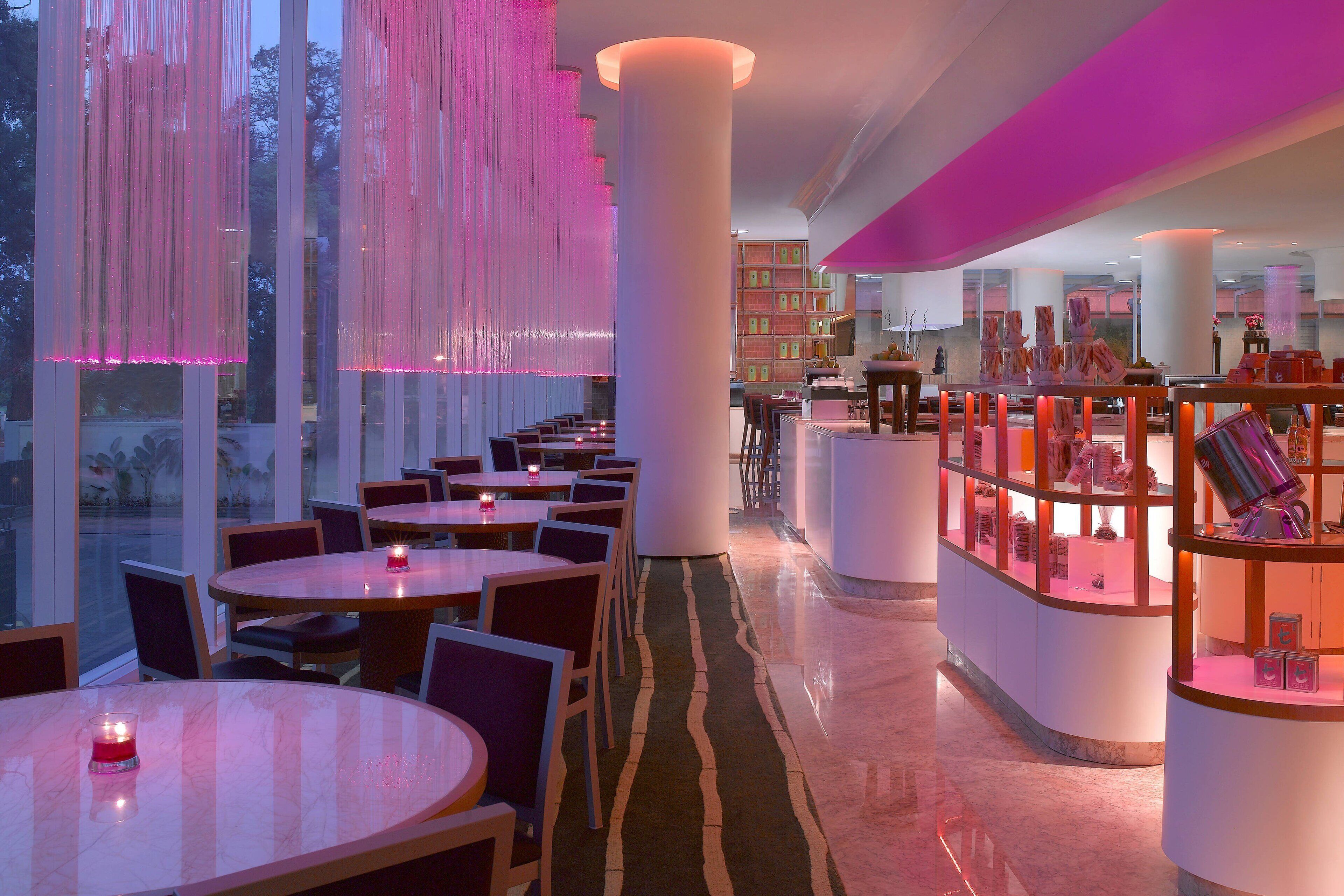 Un interior de restaurante moderno con mesas redondas, sillas y una zona central de exhibición con vitrinas.