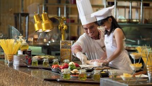A chef preparing food in a kitchen with various ingredients and cooking utensils visible. - JW Marriott Hotel Medan (Medan)