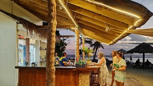 A beachside bar with a wooden structure and a thatched roof, overlooking the ocean. - Hideaway Island Resort (Hideaway Island)