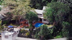 A residential property with a swimming pool surrounded by lush greenery, a covered patio, and a small tower-like structure. - Hideaway Island Resort (Hideaway Island)