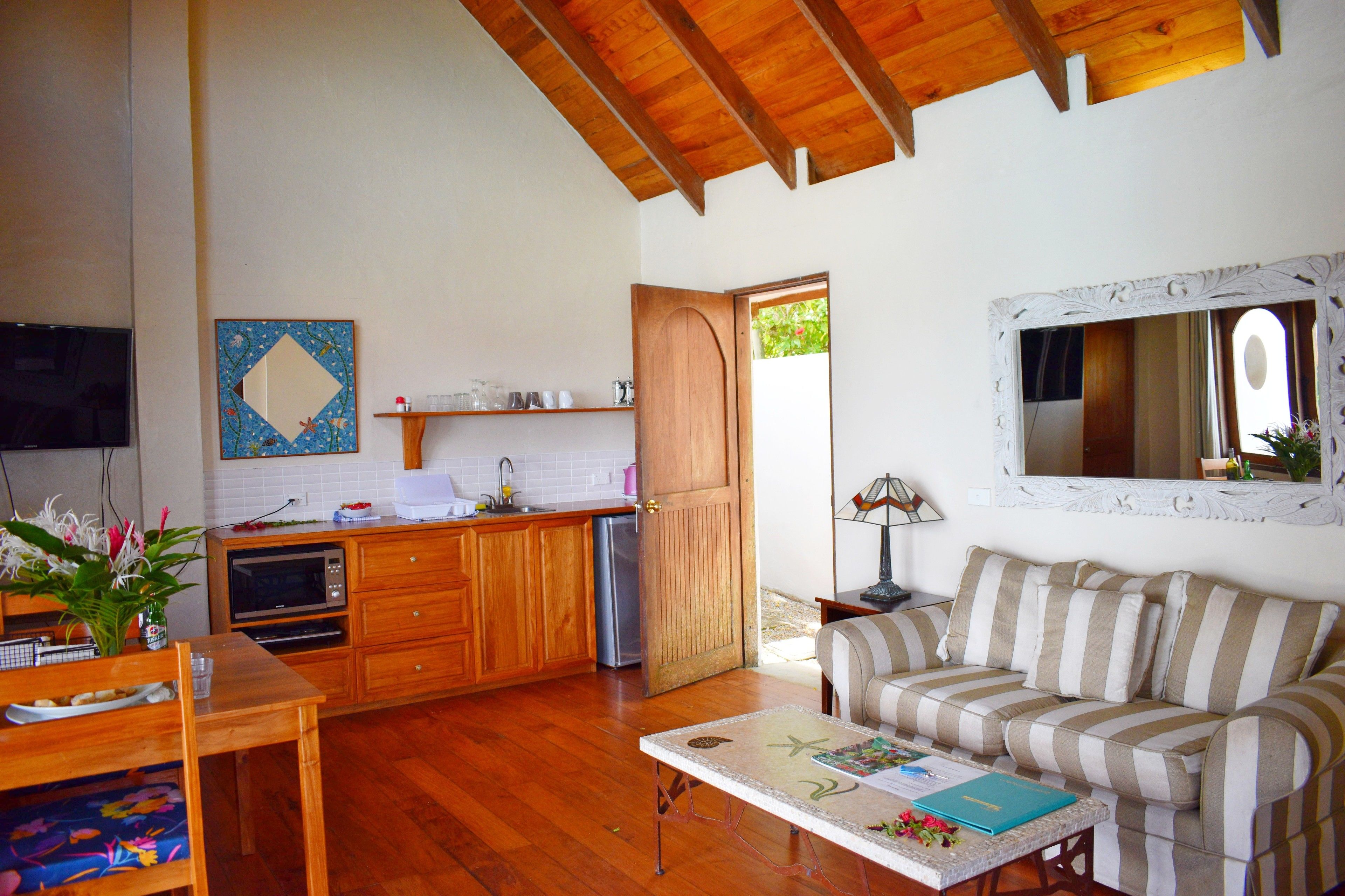 Una sala de estar acogedora con suelo de madera, un sofá a rayas, una mesa de centro y un televisor.