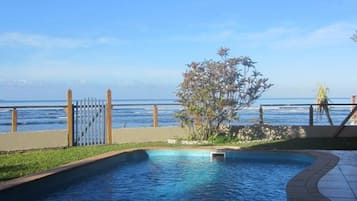Una piscina al aire libre, sombrillas, sillones reclinables de piscina