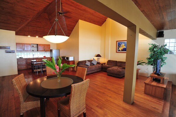 A spacious living area with a dining table, chairs, a sofa, and a TV stand.