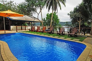 Una piscina al aire libre, sombrillas, sillones reclinables de piscina