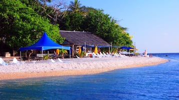 Een privéstrand, wit zand, ligstoelen aan het strand, parasols