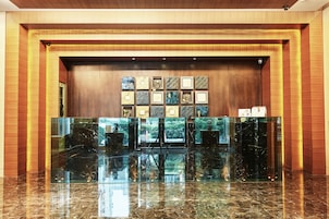 A lobby with a marble reception desk, framed artwork on the wall, and a wooden accent wall.