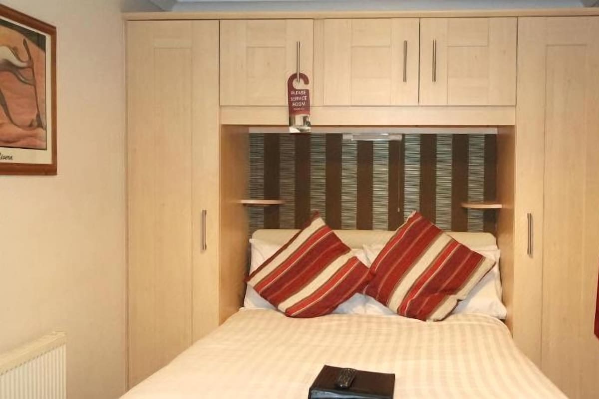 A bedroom with a bed, a wardrobe, and a window with curtains.
