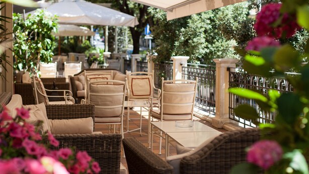 An outdoor seating area with wicker furniture, white cushions, and a table.