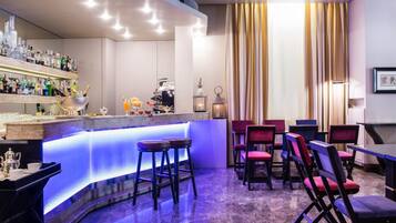 Zona de bar con mostrador, taburetes y una variedad de botellas y copas.