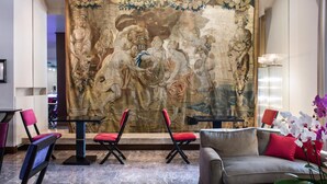 A lobby with a large mural, seating area, and a chandelier.