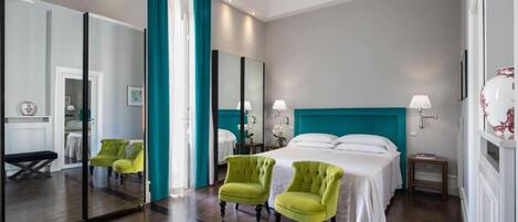 A hotel room with a large bed, two chairs, a nightstand, and a mirror.