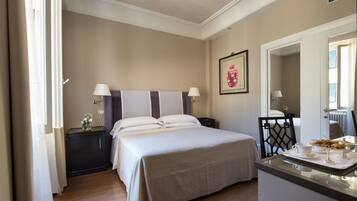 A hotel room with a bed, bedside tables, a desk with a chair, and a mirror.