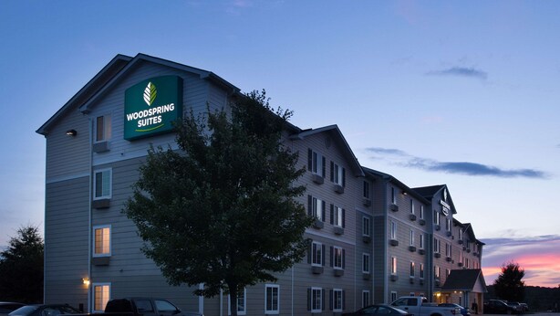 A multi-story hotel with a prominent sign for "Woodspring Suites."