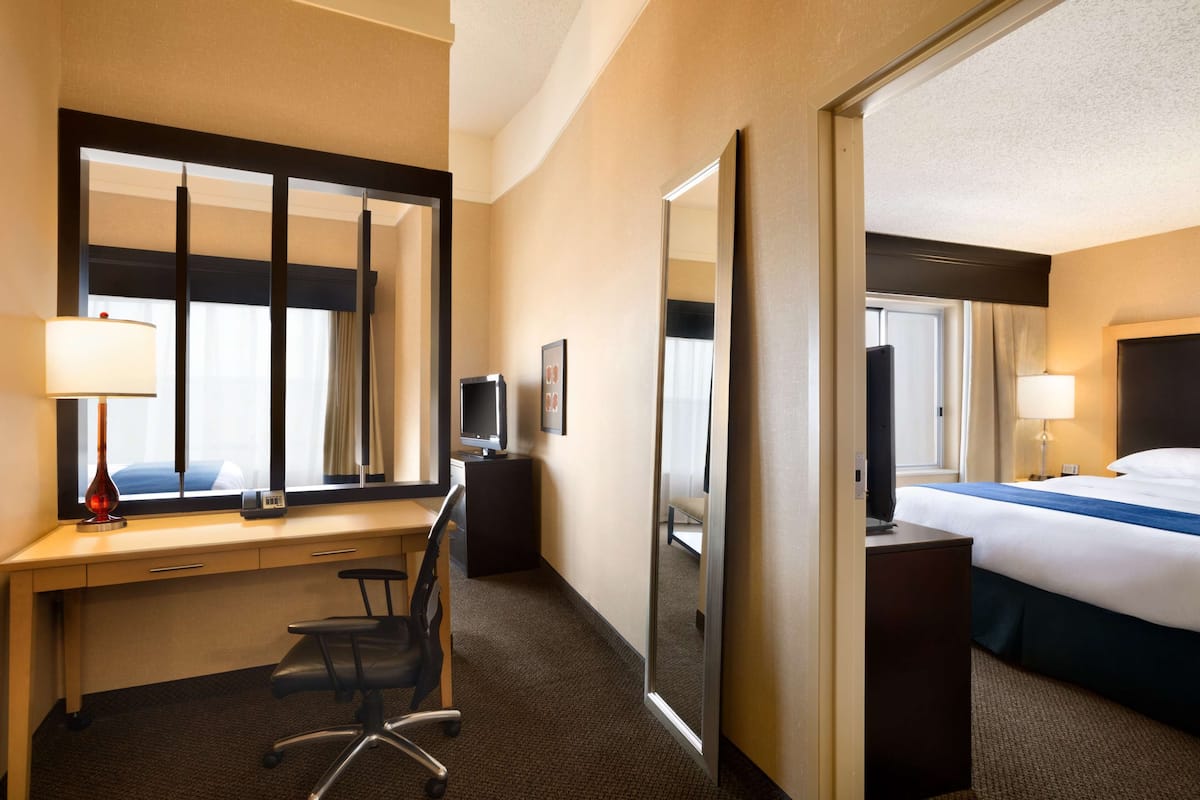 Una habitación de hotel con escritorio, silla, cama y un espejo grande.