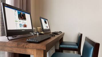 A wooden desk with two monitors, a keyboard, and a mouse.