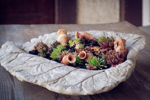 A stone planter with succulents and terracotta pots on a wooden surface. - Hotel Alpina (Kandersteg)