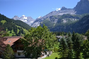 Un hôtel offrant une vue sur les montagnes, entouré d’une végétation luxuriante et de sommets enneigés.